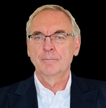 A person wearing glasses and a suitDescription automatically generated